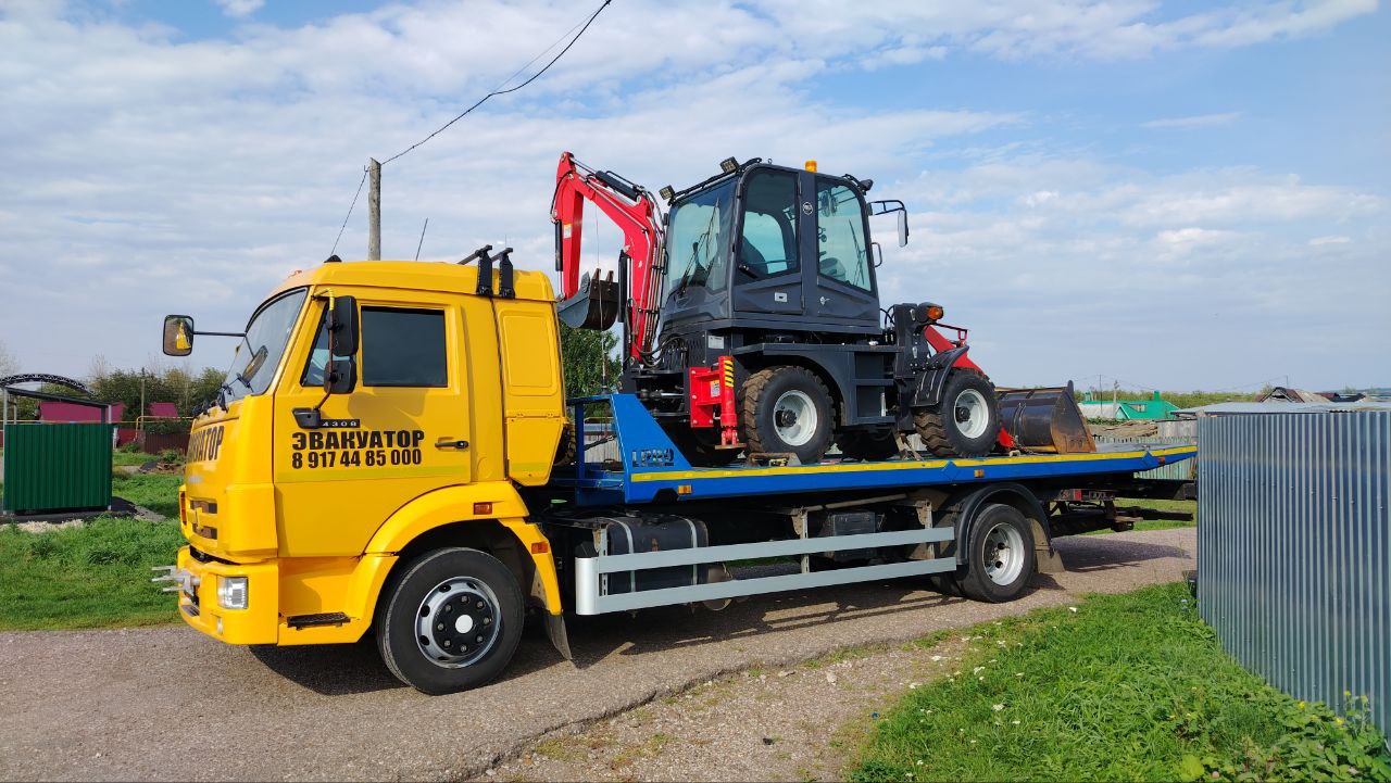 Эвакуатор АвтоДруг перевозит трактор по трассе